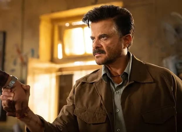 Anil Kapoor in a military-style jacket, standing in a dimly lit room, looking into the distance.