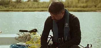 Screenshot from the Closure trailer showing a father on a boat with a drone over the Vistula River at dusk.