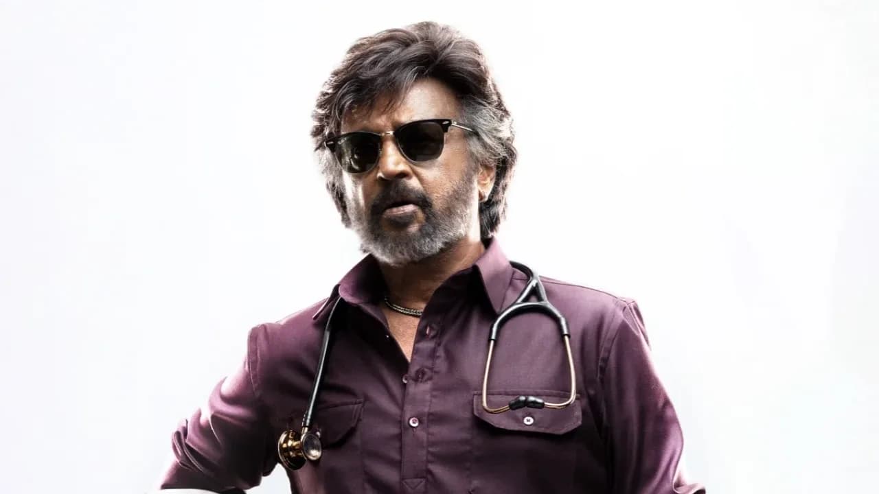 Rajinikanth in a dramatic pose, standing against a city skyline, wearing a sharp suit, with 'Dharman' logo in bold text below.