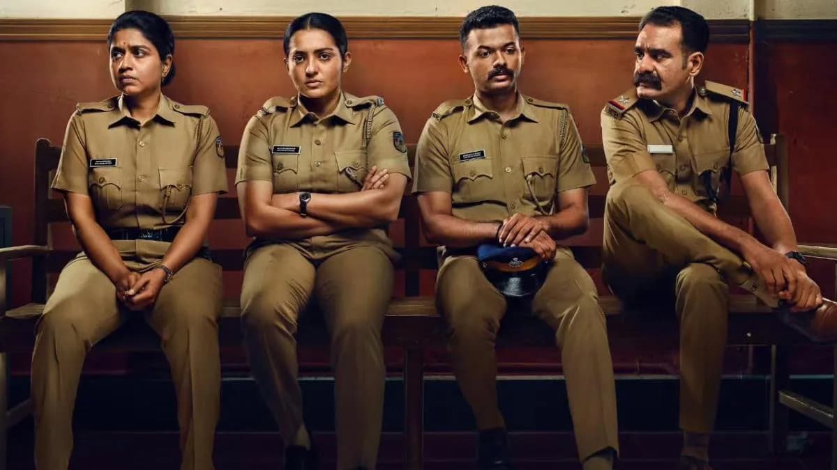 Parvathy Thiruvothu in a tense scene from Pradhama Drishtya Kuttakkar, holding a gun, surrounded by police uniforms.