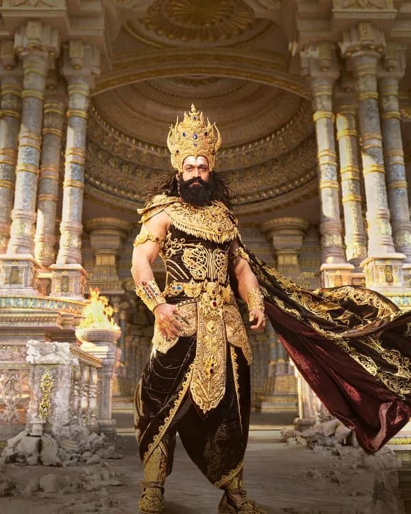 Yash as Ravana wearing a bright gold crown, pearl necklaces and gold bracelets, with an intense gaze against a dark background